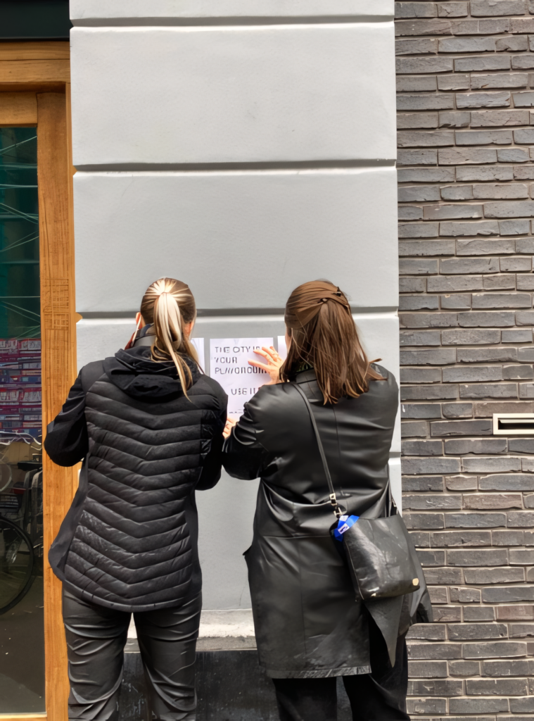 two students putting posters on a wall