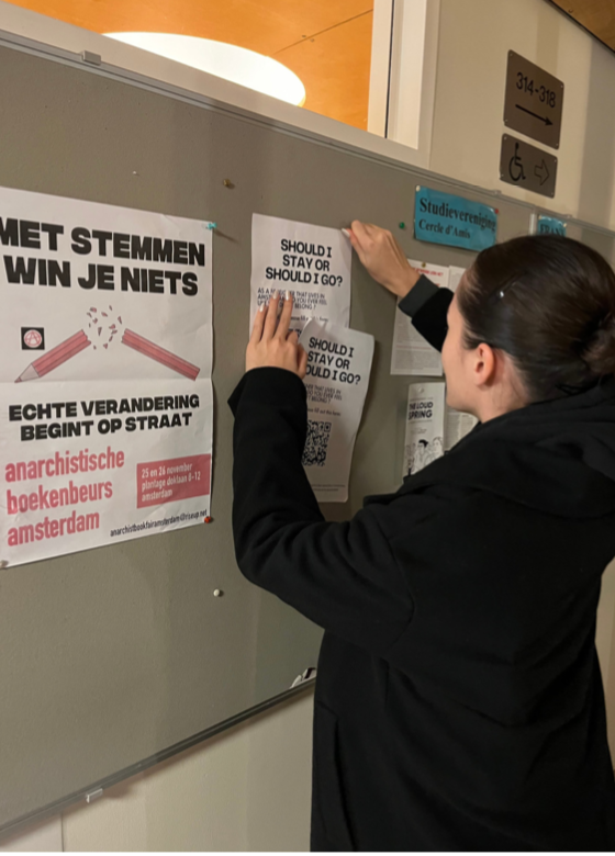 A student pinning a poster on a pin board.