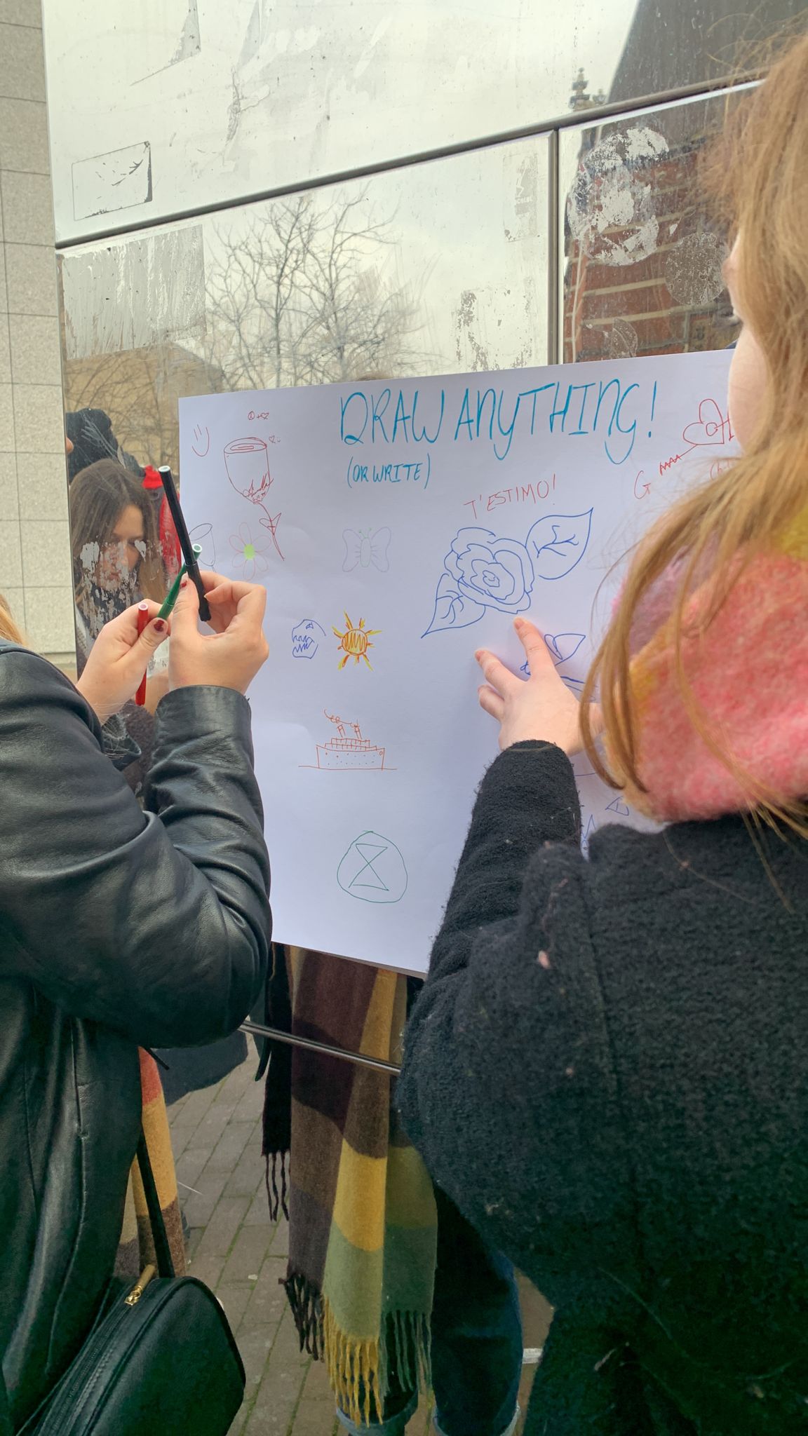 Students holding a big poster that passersby people can write and draw on 