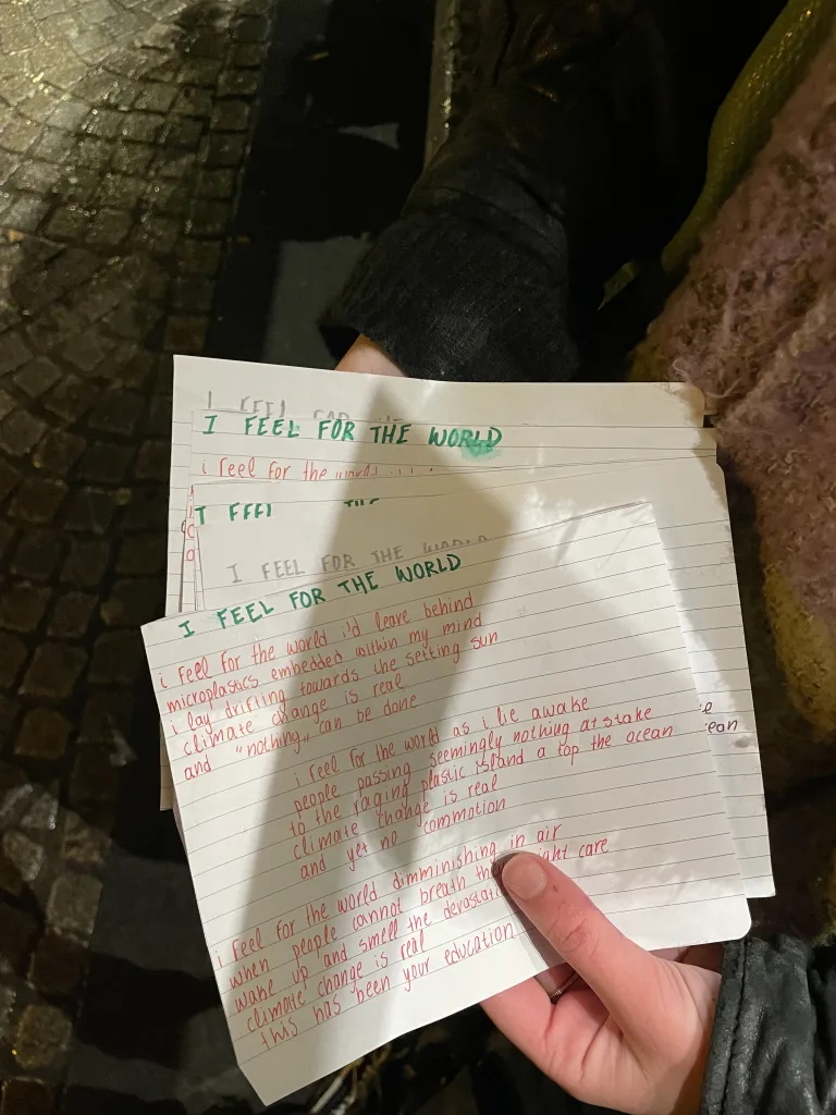 a student holding the copies of the same "I Feel For the World" poem