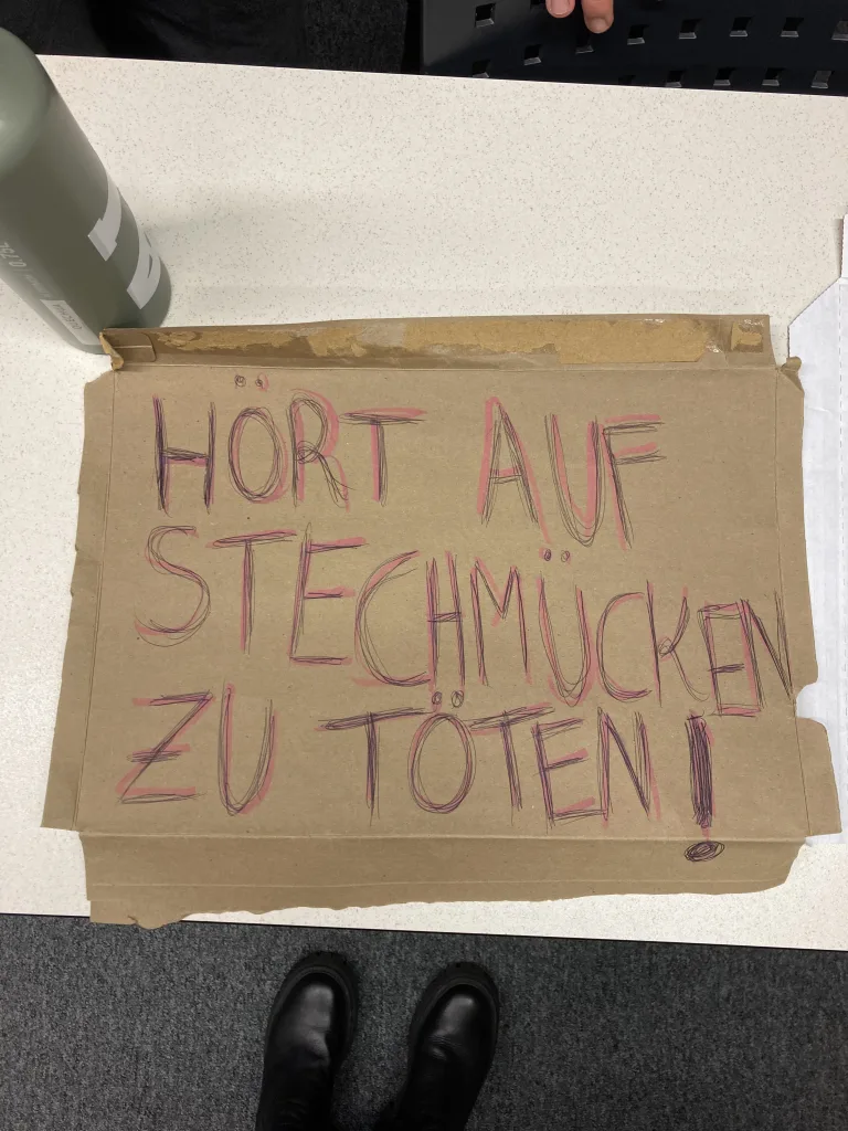 A sign that reads "Hört Auf Stechmücken Zu Töten!"
