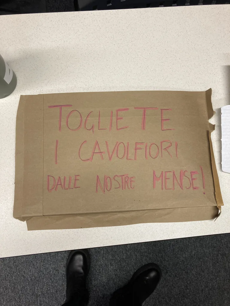 A sign that reads "Togliete I Cavolfiori Dalle Nostre Mense!". 