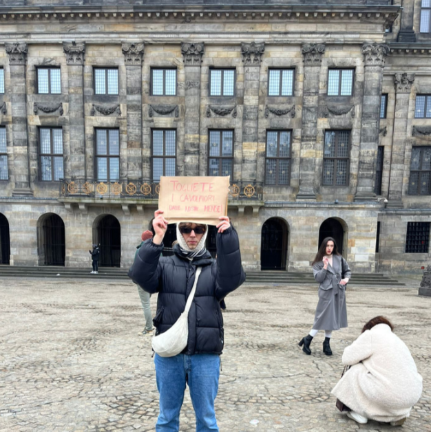 A kid holding a sign in the Dam square. 